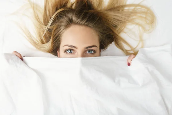 Primer plano de una mujer escondida en su cama en casa — Foto de Stock
