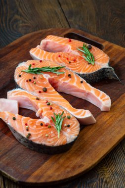 Kesme tahtasında baharatlı çiğ somon balığı bifteği. Kesme tahtasında baharatlı çiğ somon balığı bifteği. Koyu renk ahşap.