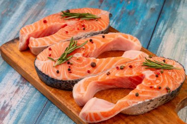 Üç parça çiğ somon, baharat, yemek, eski püskü mavi masada tuz biberiyesi, üst manzara. Balık yemi pişirme hazırlığı. Somon bifteği.