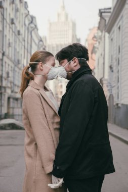 Birbirine aşık bir çift, koruyucu tıbbi maskeli bir adam ve kadın sokakta yüz yüze. Çevre kirliliği kavramı. Guy, kız Çin salgınına karşı koronavirüs, virüs koruması