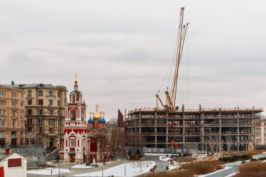 İnşaat vinci inşaat alanında. Kış, şehir caddesinde bitmemiş bir bina..