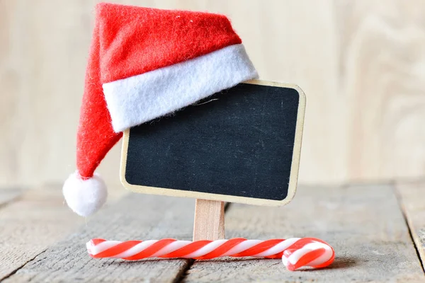 Weihnachtsmannmütze auf kleiner Tafel — Stockfoto