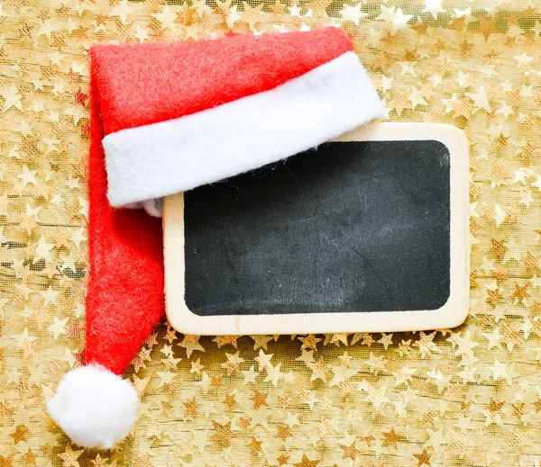 Weihnachtsmannmütze auf kleiner Tafel — Stockfoto