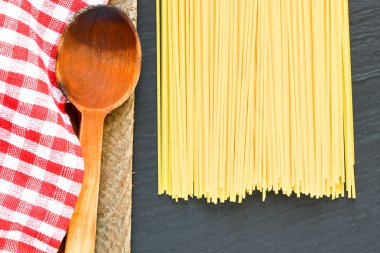 Damalı masa örtüsü ve ahşap zemin üzerine kaşık ile İtalyan ham pasta 