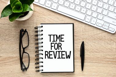 Yüzük bağlı defter ile gözlük, yeşil bitki ve klavye üzerinde değerlendirme zamanı kelime