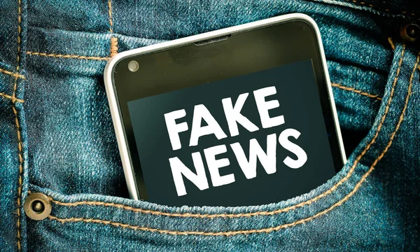 Fake news inscription on phone screen / Smartphone in front jeans pocket with good news inscription