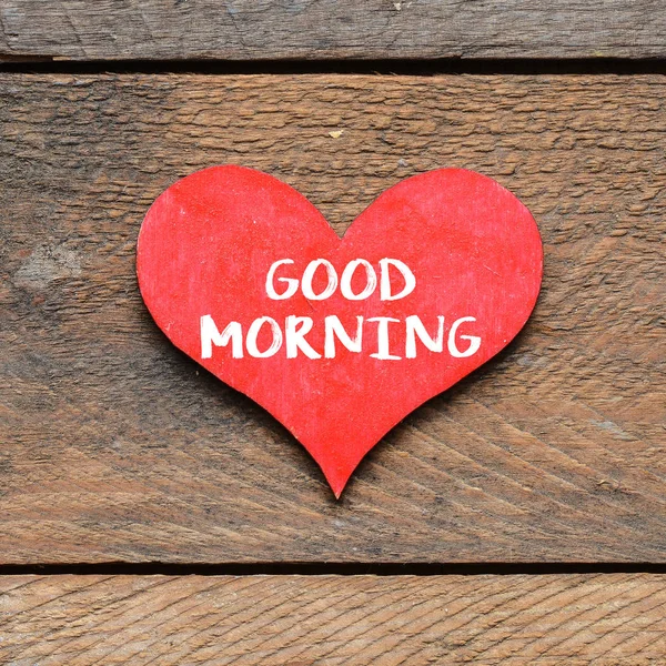 Closeup of red heart with text good morning over wooden surface