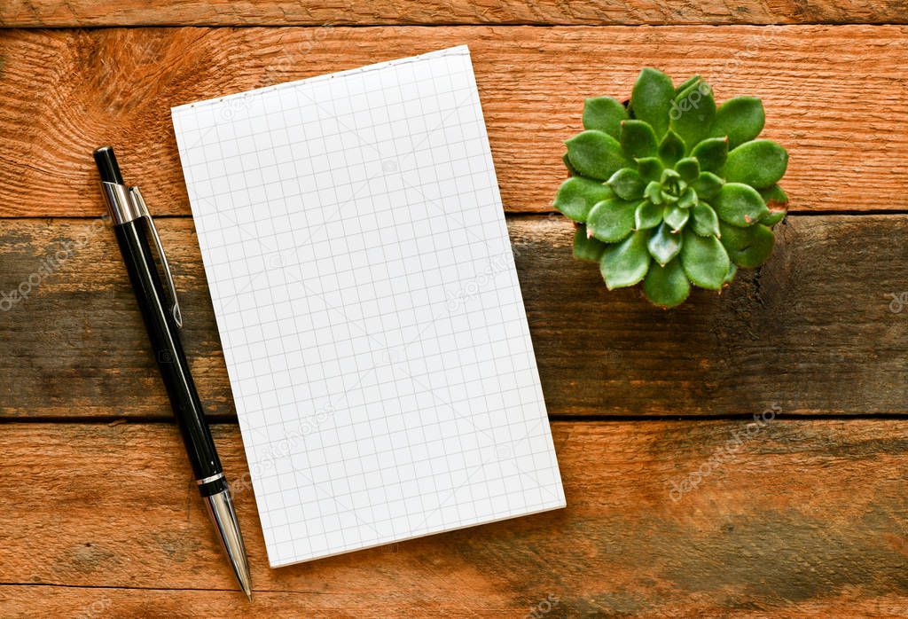 notebook with pen with plant on wooden background, top view. Business concept