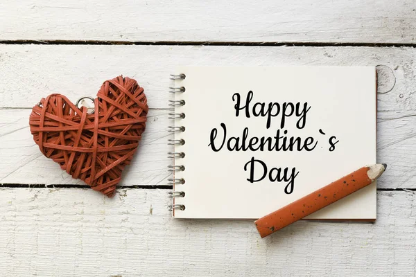 ハッピーバレンタインデーのメッセージ 螺旋状のメモ帳のテキスト右側にペンで Happy Valentine Day と愛の左側のシンボルに2つの織りの心 — ストック写真