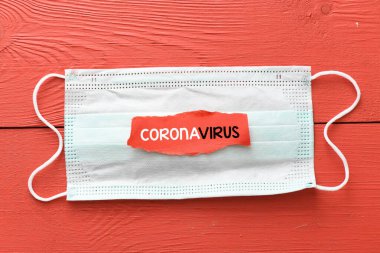 CORONAVIRUS. Kırmızı bir masada bulunan koruyucu bir maskenin üzerine yazılmış bir kelime. Roman Coronavirus - 2019-NCoV, WUHAN virüs konsepti