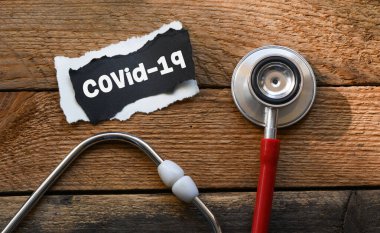 Siyah kağıt üzerinde COVID-19 metni, steteskop. Covid-19 veya Coronavirus Kavramı.