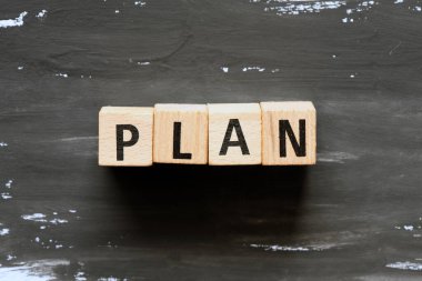 Tahta bloklar ve siyah arka plan için plan kelimesi. İş dünyasında kavram.