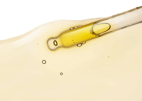 Liquid yellow gel or serum drop and pipette on white isolated background