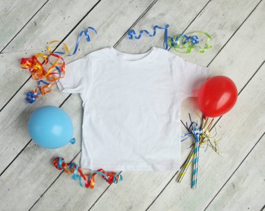 Düz beyaz çocuk çocuklar t gömlek balonları, flamalar, doğum günü kutlaması için mockup yatıyordu ve parti süsleri