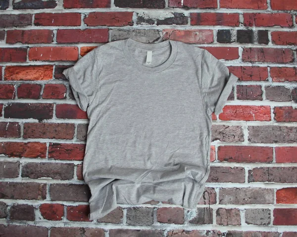 Flat lay maqueta de camiseta gris sobre fondo de ladrillo —  Fotos de Stock