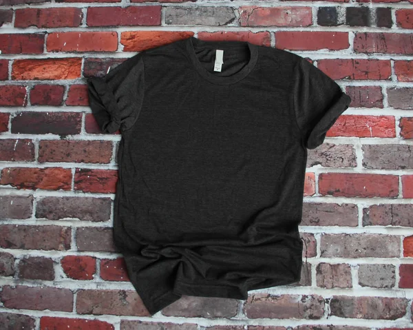 Flache Lay-Attrappe eines anthrazitgrauen T-Shirts auf Ziegelgrund lizenzfreie Stockfotos