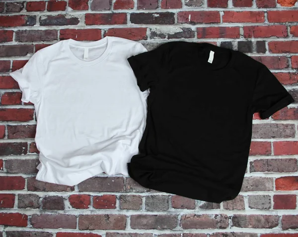 Flat lay mockup de tshirt branca e tshirt preta no backgr tijolo Imagem De Stock