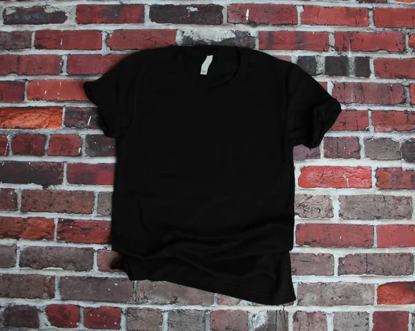 Flat lay mockup de camisa preta no fundo de tijolo para o produto Fotos De Bancos De Imagens Sem Royalties