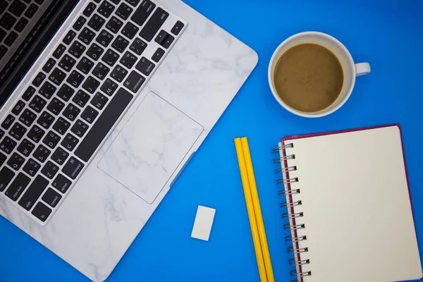 Office desk table with notebook, stationery and coffee cup. Top view