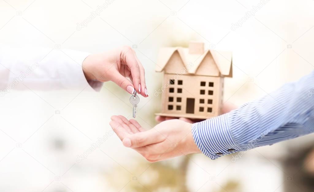 Woman is handing a house key to a man.