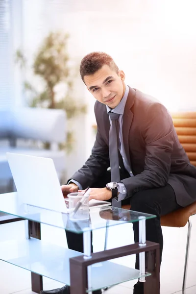 Успешный молодой бизнесмен печатает на ноутбуке на рабочем месте — стоковое фото