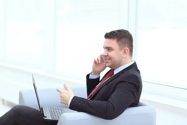 Щасливий молодий бізнесмен читає документи і розмовляє по телефону в офісі — стокове фото