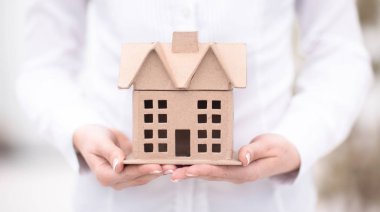 Emlak kavram - bir kadın bir evin bir mimari model tutuyor