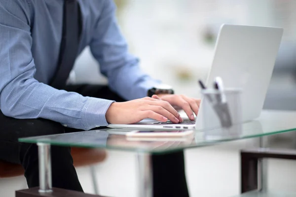 Young business man working on a laptop at his desk in the office, in view of the profile against the window — Stock Photo, Image