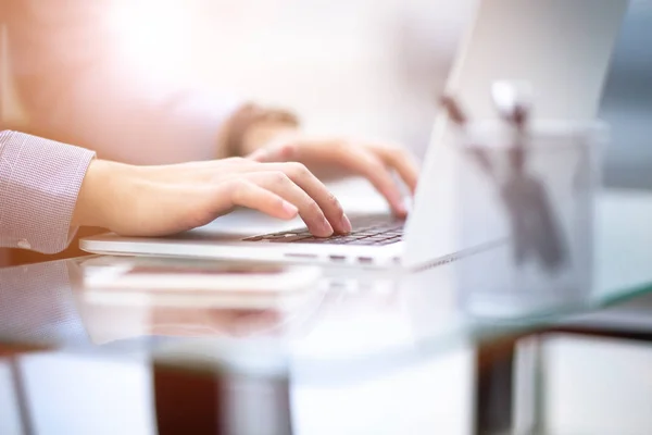 Young business man working on a laptop at his desk in the office, in view of the profile against the window — Stock Photo, Image