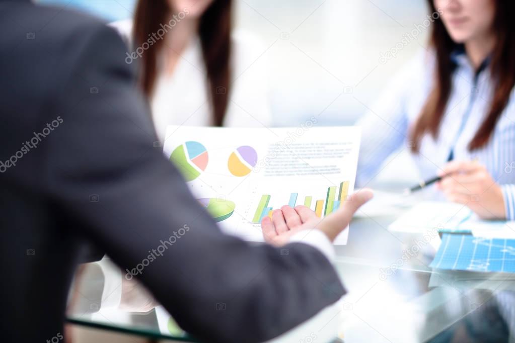 businessman hand pointing at graph document during discussion at meeting.