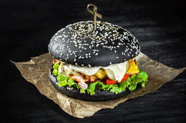 Domuz pastırmalı siyah sığır etli burger. Kara tahta arkaplan