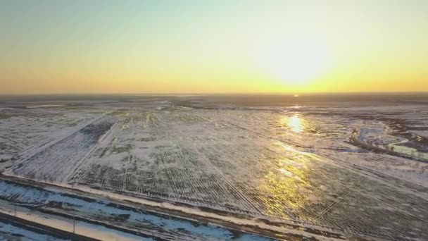 Campos cobertos de neve ao pôr-do-sol a partir de uma vista de olhos de pássaros — Vídeo de Stock