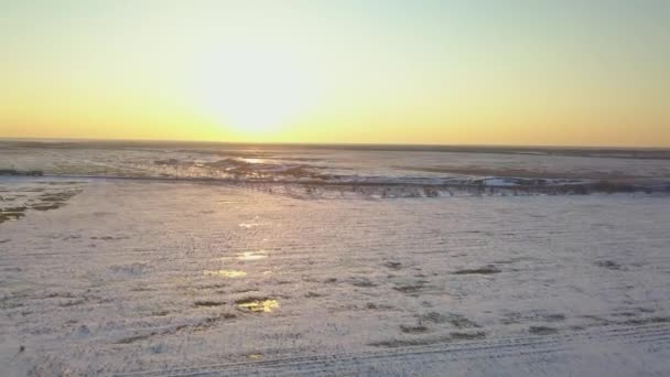 O trem está se movendo através de campos cobertos de neve ao pôr do sol — Vídeo de Stock