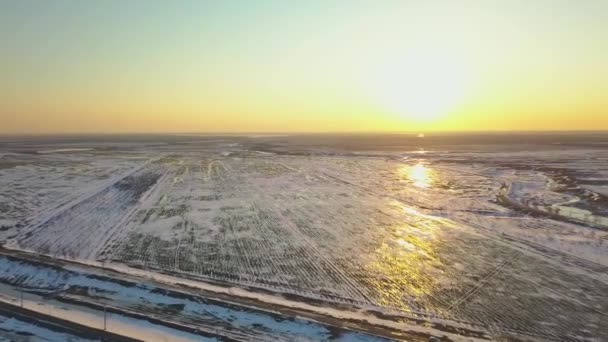 Campos cobertos de neve ao pôr-do-sol a partir de uma vista de olhos de pássaros — Vídeo de Stock