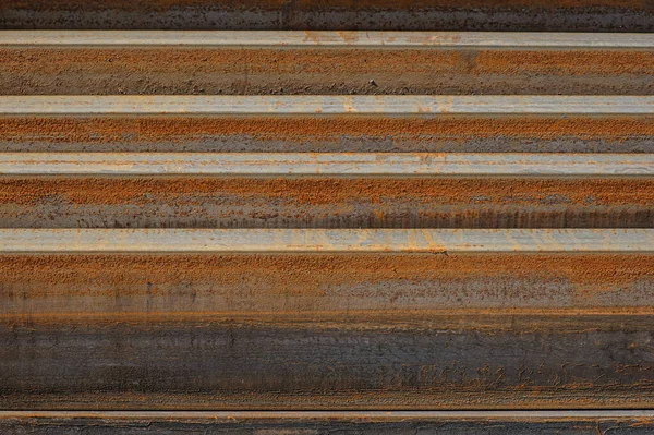 Racks of metal profiles. Metal is stored in an open warehouse. Wet and rusty on the street. Old grunge background made of rusty iron for shooting flatleys on the table