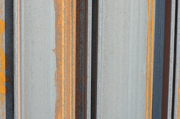 Racks of metal profiles. Metal is stored in an open warehouse. Wet and rusty on the street. Old grunge background made of rusty iron for shooting flatleys on the table