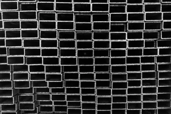 Fondo cerrar tubos cuadrados de metal en stock. Montones de nuevos tubos de acero cuadrados en la fábrica — Foto de Stock