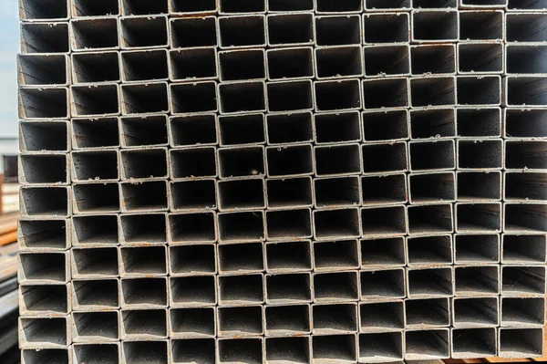 Background close up metal square pipes in stock. Stacks of new square steel pipes at the factory — Stock Photo, Image