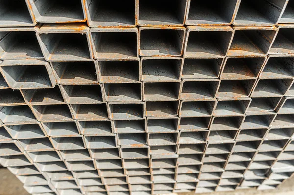Fondo cerrar tubos cuadrados de metal en stock. Montones de nuevos tubos de acero cuadrados en la fábrica —  Fotos de Stock