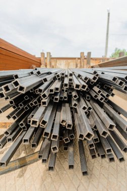 Metal profil yığınları. Metal açık bir depoda saklanıyor. Sokaklar ıslak..