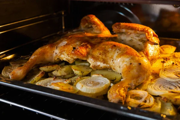 Fried chicken with baked potatoes and onions in the oven — Stock Photo, Image