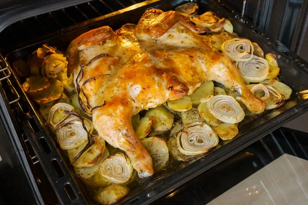 Fried chicken with baked potatoes and onions in the oven — Stock Photo, Image