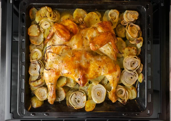 Fried chicken with baked potatoes and onions in the oven. The view from the top — Stock Photo, Image