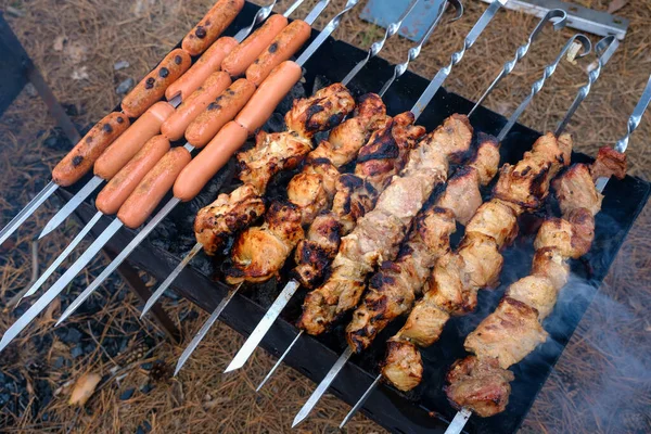 Preparación de shish kebab y salchichas en parrilla de carbón al aire libre — Foto de Stock