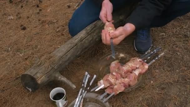 Man stringing kebab on a skewer. Cooking kebabs on the nature — Stock Video