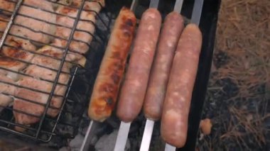 Izgarada barbekü ve sosisler ızgarada kızartılmış, yakın plan. Açık hava barbeküsü