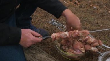 Şişe kebap bağlayan bir adam. Doğada kebap pişirmek.