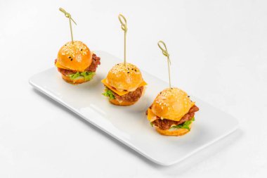 Beyaz arka planda cam tabakta mini sandviçler. Yemek servisi.