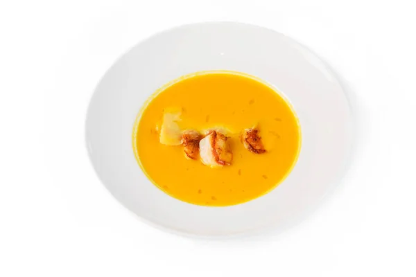 Pumpkin soup with shrimps in a plate on white background. Top view, close-up — Stock Photo, Image