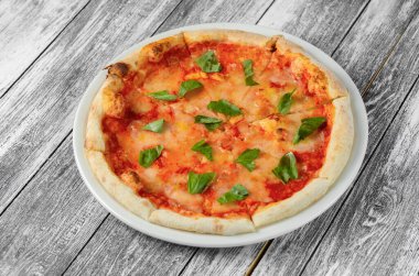 Domates soslu pizza ve ahşap arka planda fesleğen. Üst görünüm, yakın çekim